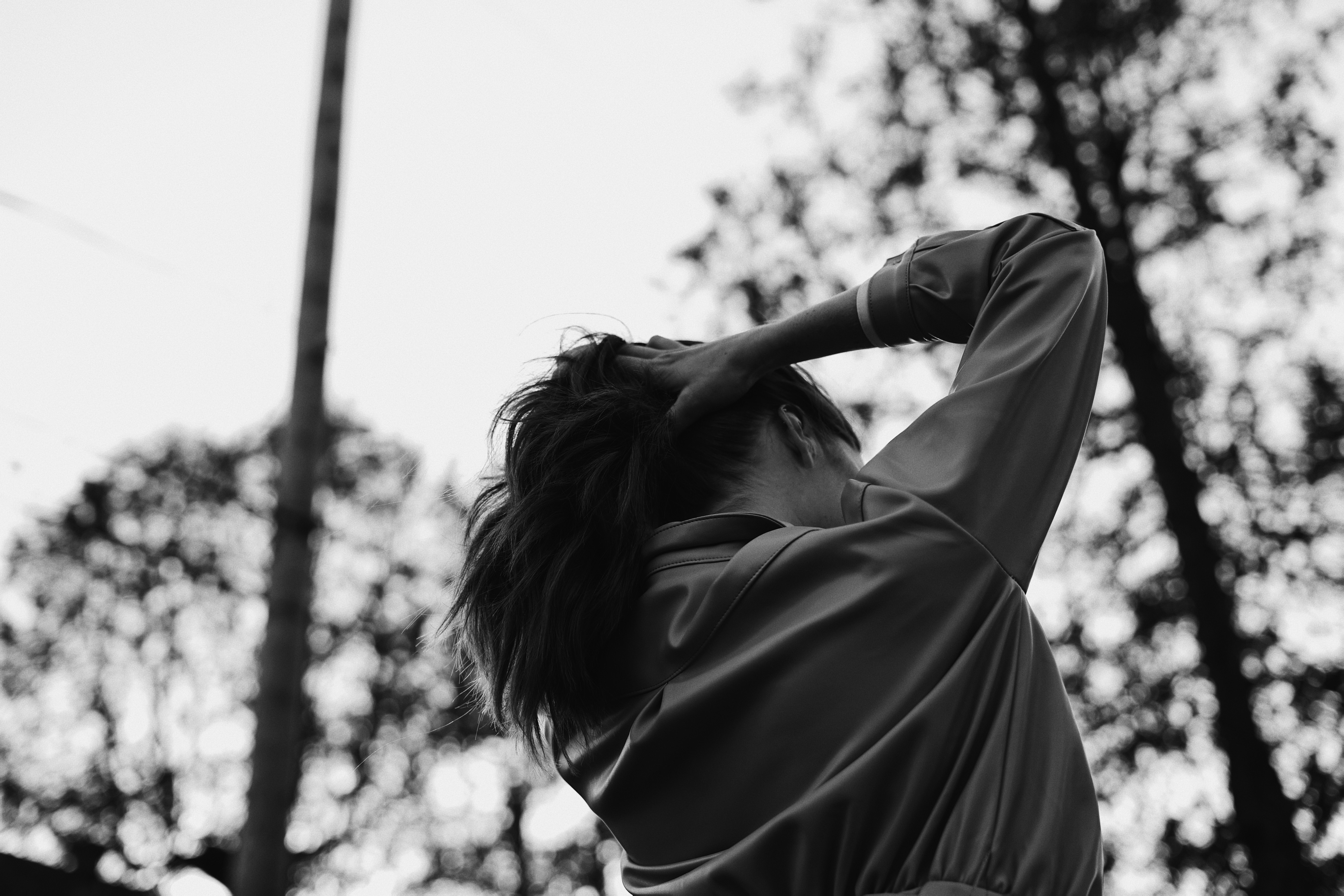 grayscale photo of woman in long sleeve shirt covering her face with her hair